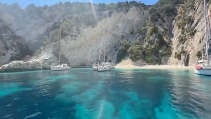 Aerial film over yachts anchored in clear turquoise water in the Ionian Sea
