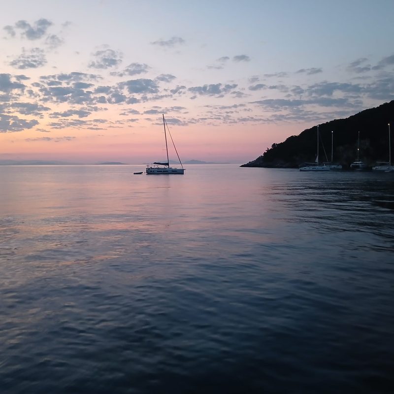 Pastel pink and blue dawn over yachts anchored in a calm Ionian bay
