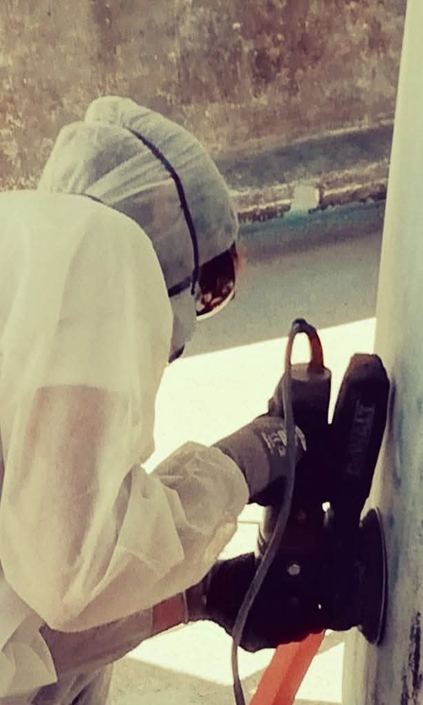 AIyachts technician in protective overalls sanding a yacht hull during winter maintenance