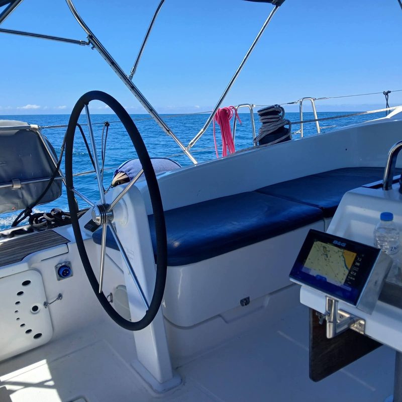 Wheel and cockpit of a managed sailing yacht under way on open blue water