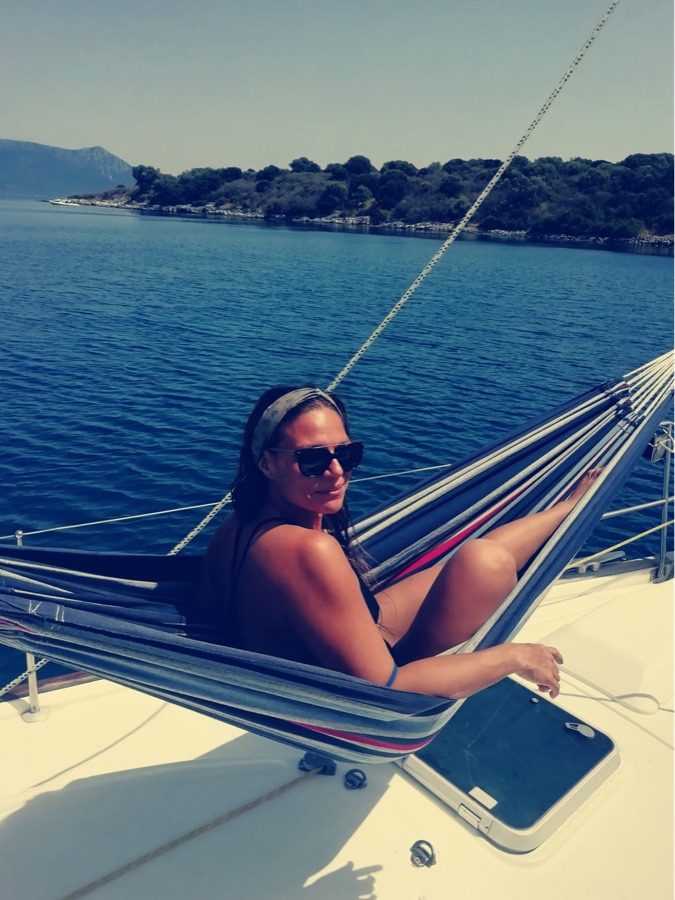 Guest relaxing in a hammock on the foredeck of a sailing yacht at anchor in Greece