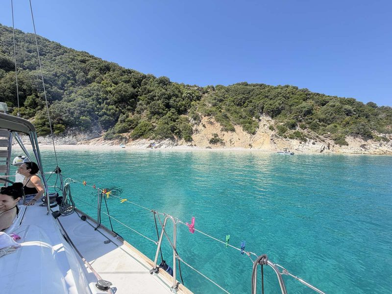 Looking forward over the bow of a charter yacht into a shallow turquoise bay before a swim stop