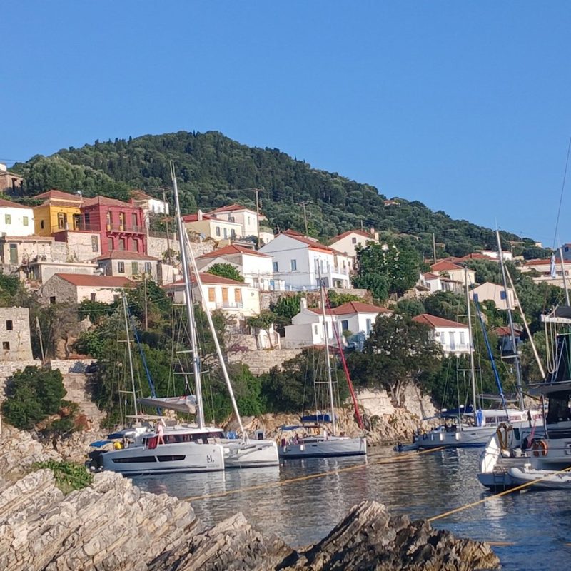 Colourful Greek island village above a small harbour full of moored sailing yachts